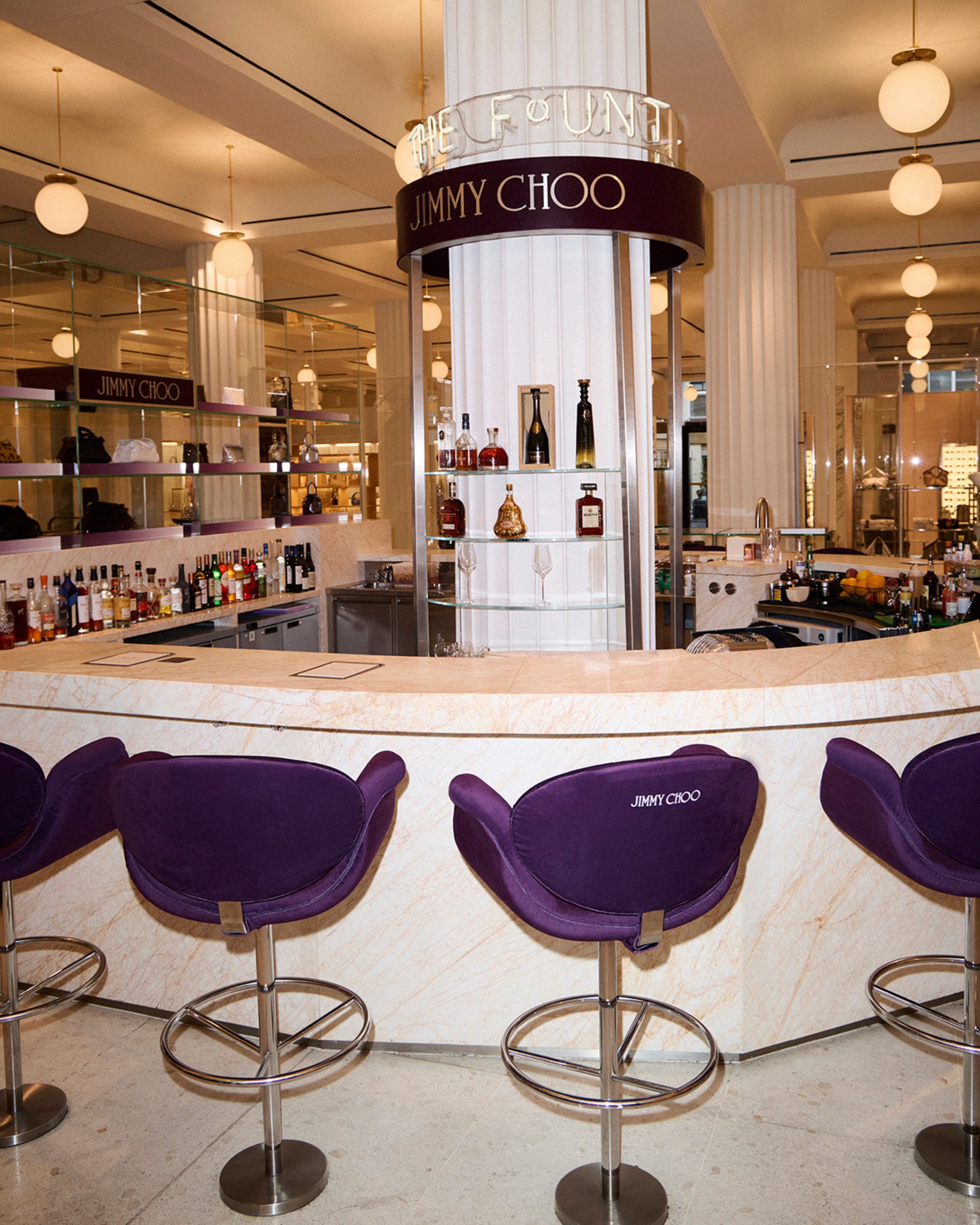Jimmy Choo bar at Selfridges with purple seating, a curved marble counter and display shelving.