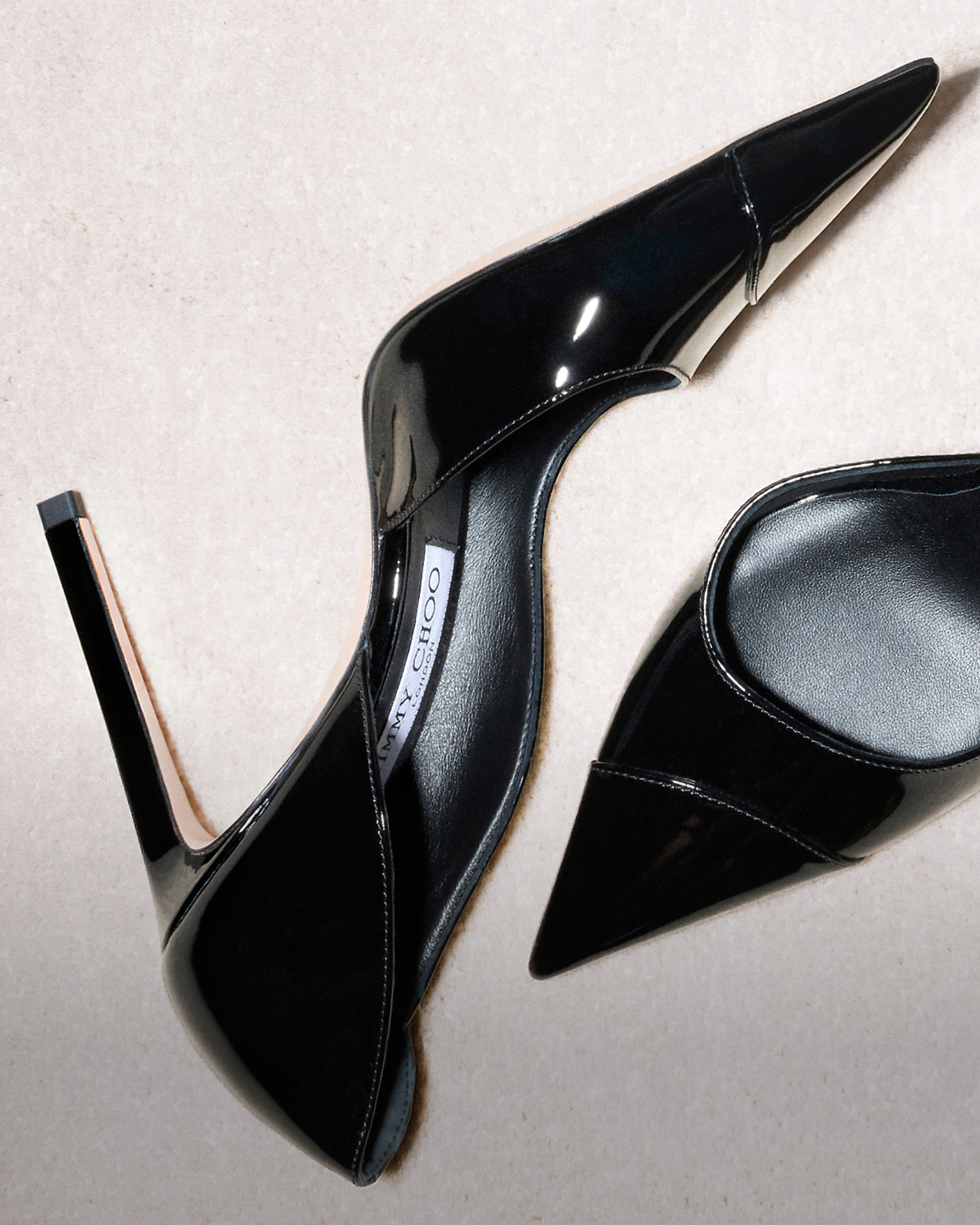Pair of black patent leather pointed-toe pumps with stiletto heels.
