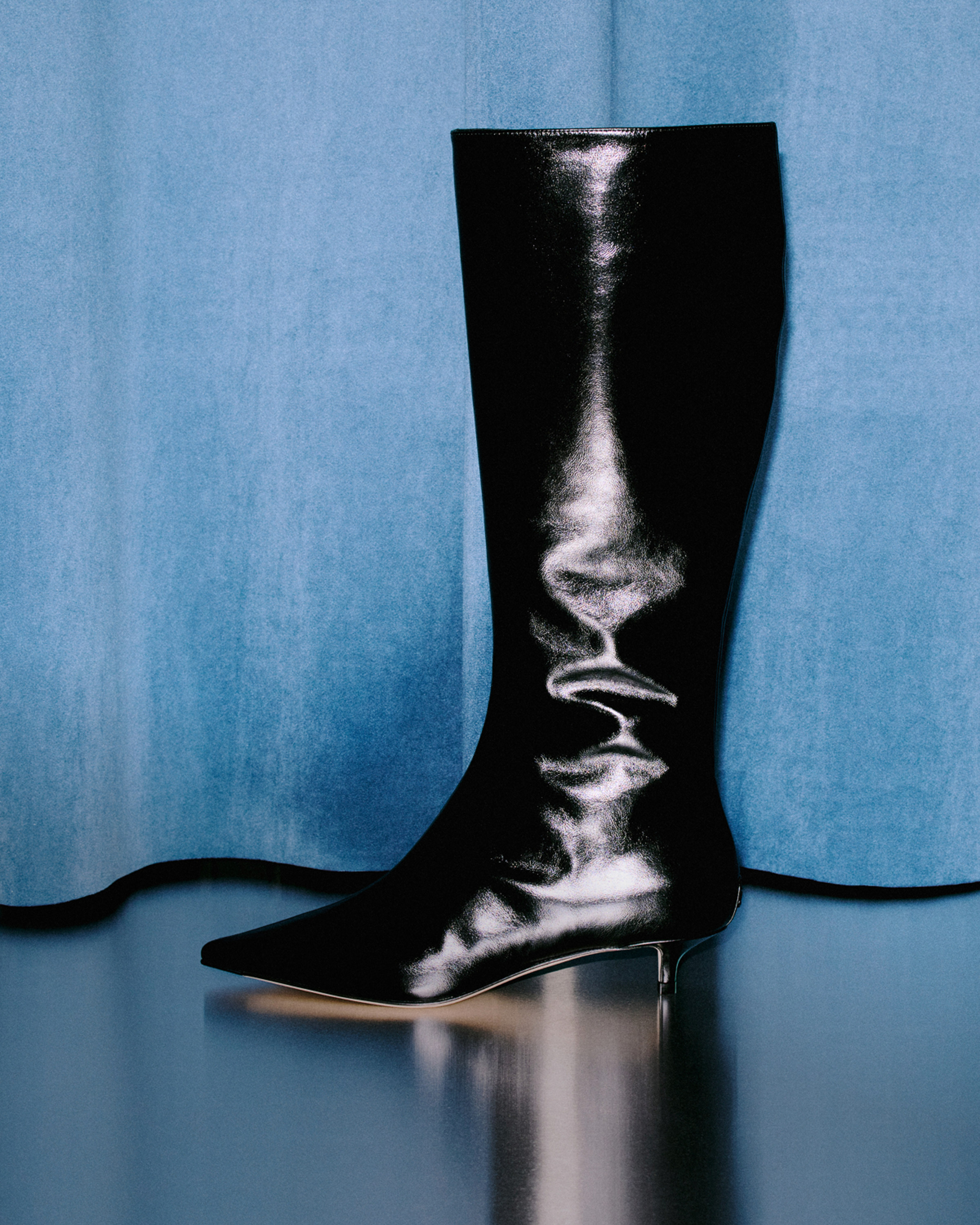 A linear over-the-knee silhouette presented in glossy eel-embossed leather.