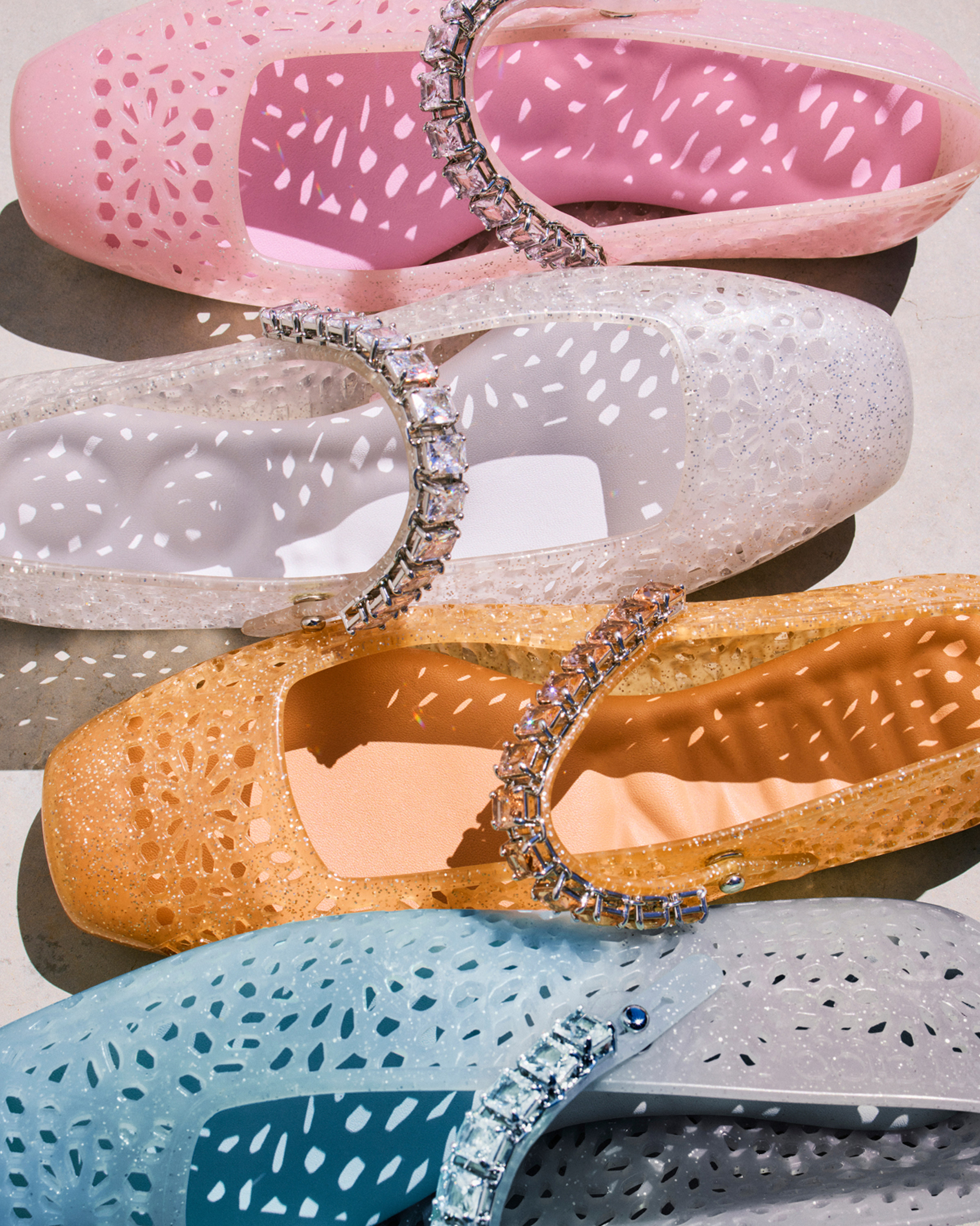 Colourful perforated jelly ballet flats with crystal straps arranged side by side.