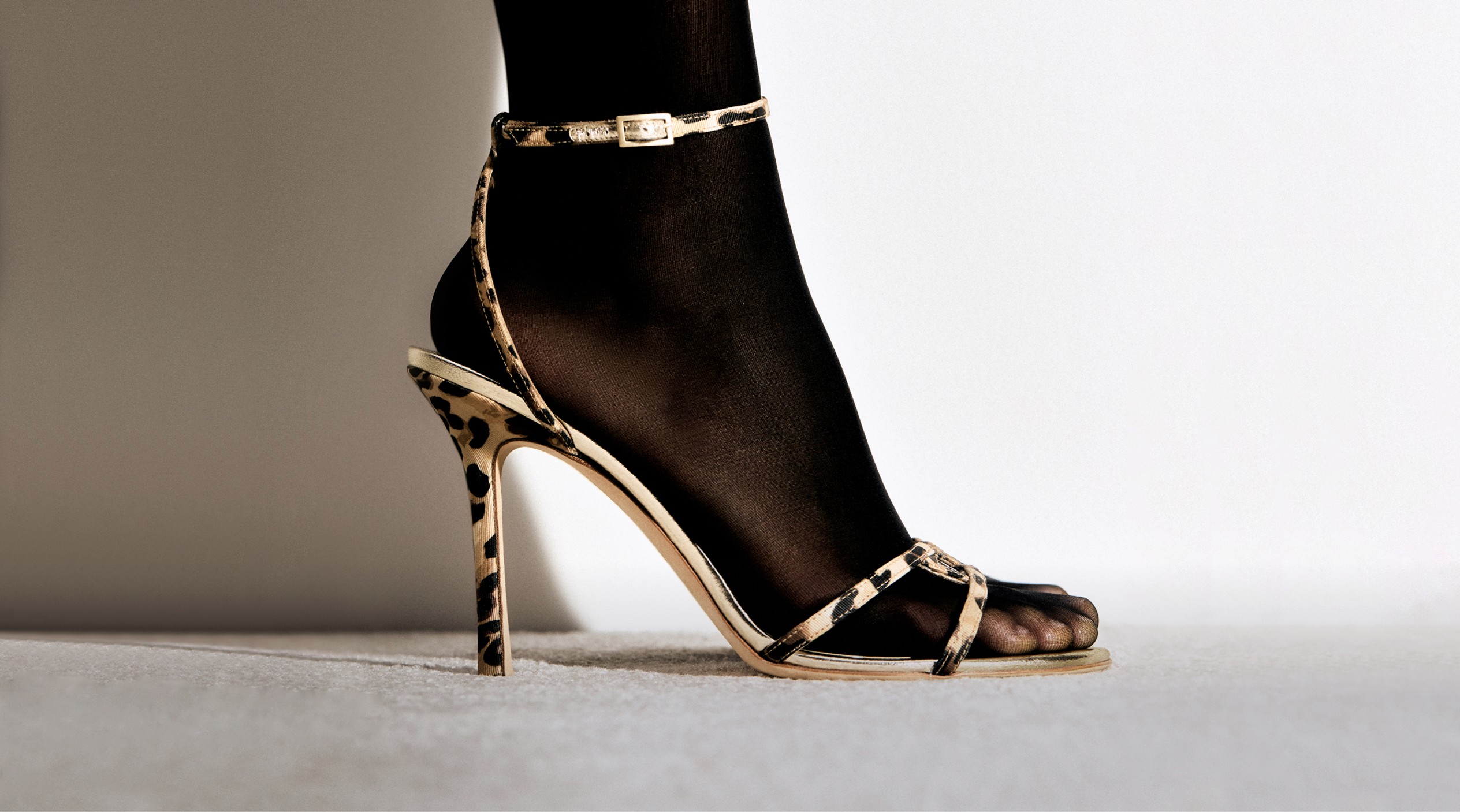A collection of vintage Jimmy Choo heeled sandals and mules from the Archive collection, featuring various textures, prints and silhouettes, including animal print, metallic and floral designs.