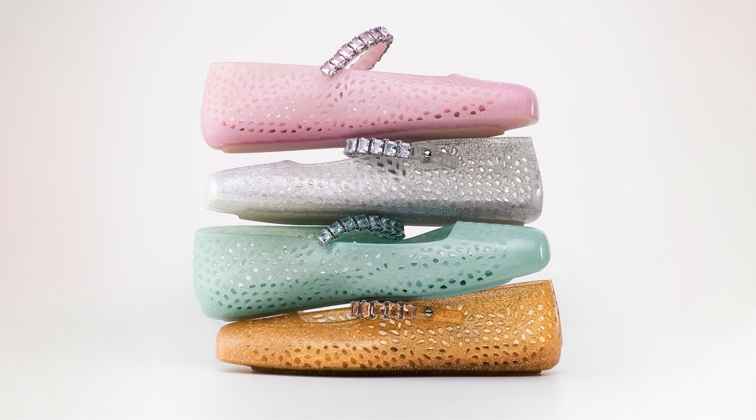 Stack of Jelly shoes in pastel tones with crystal-embellished straps.