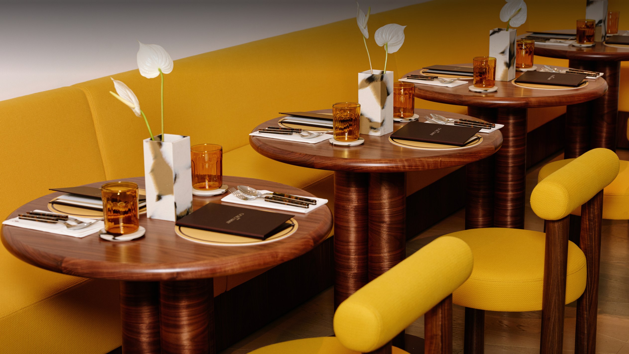 Interior view of the Jimmy Choo Caf&eacute; bar with illuminated shelving displaying rows of yellow cups and glassware.