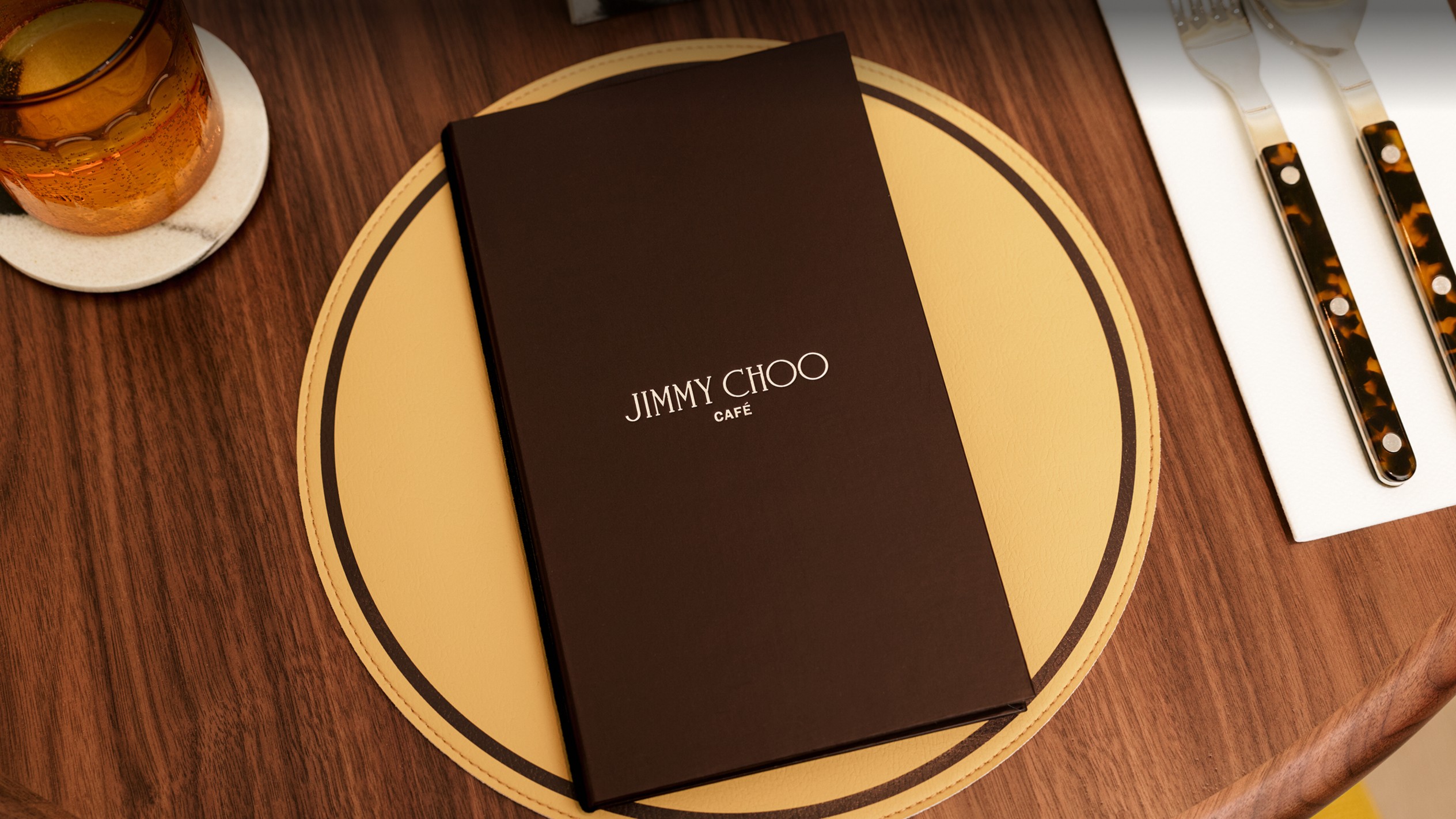 Jimmy Choo Caf&eacute; で提供される、カレーソース、白ご飯、フライドオニオンが盛り付けられた金属製のサービングディッシュと、上に持ち上げられたパパダム。