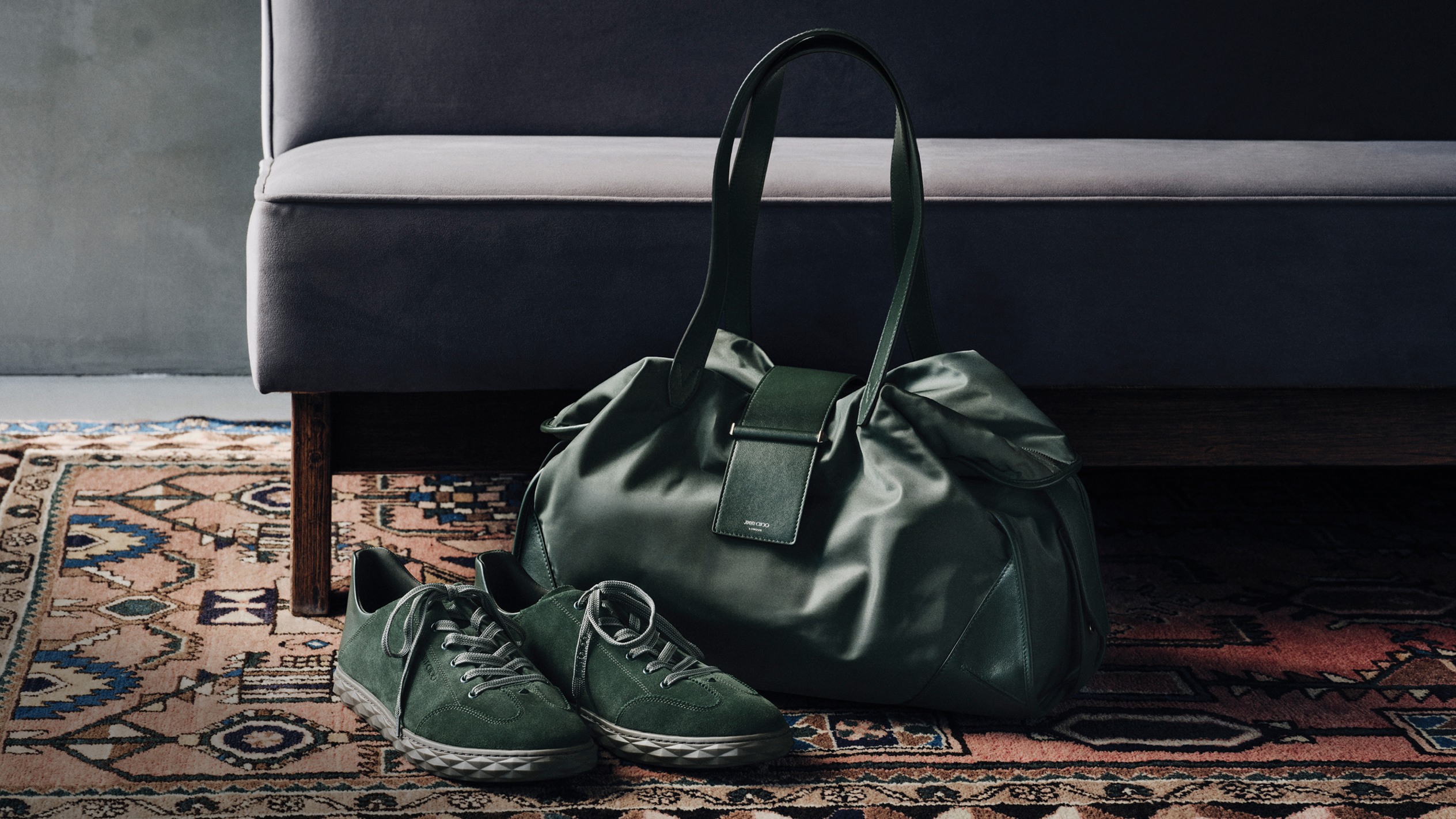 Black leather top-handle bag with stud detailing, carried with fresh flowers, styled with black trousers and white trainers.