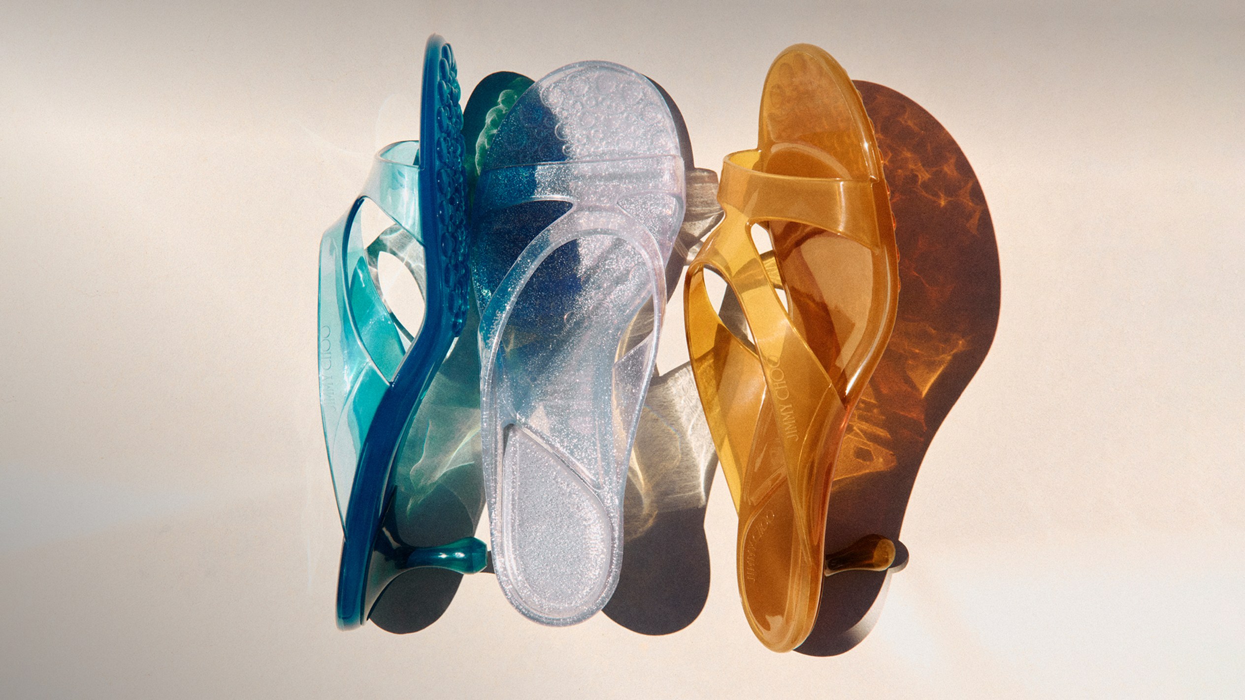 Blue, amber, clear and pink jelly ballerina flats arranged side by side, each detailed with a crystal-embellished strap.