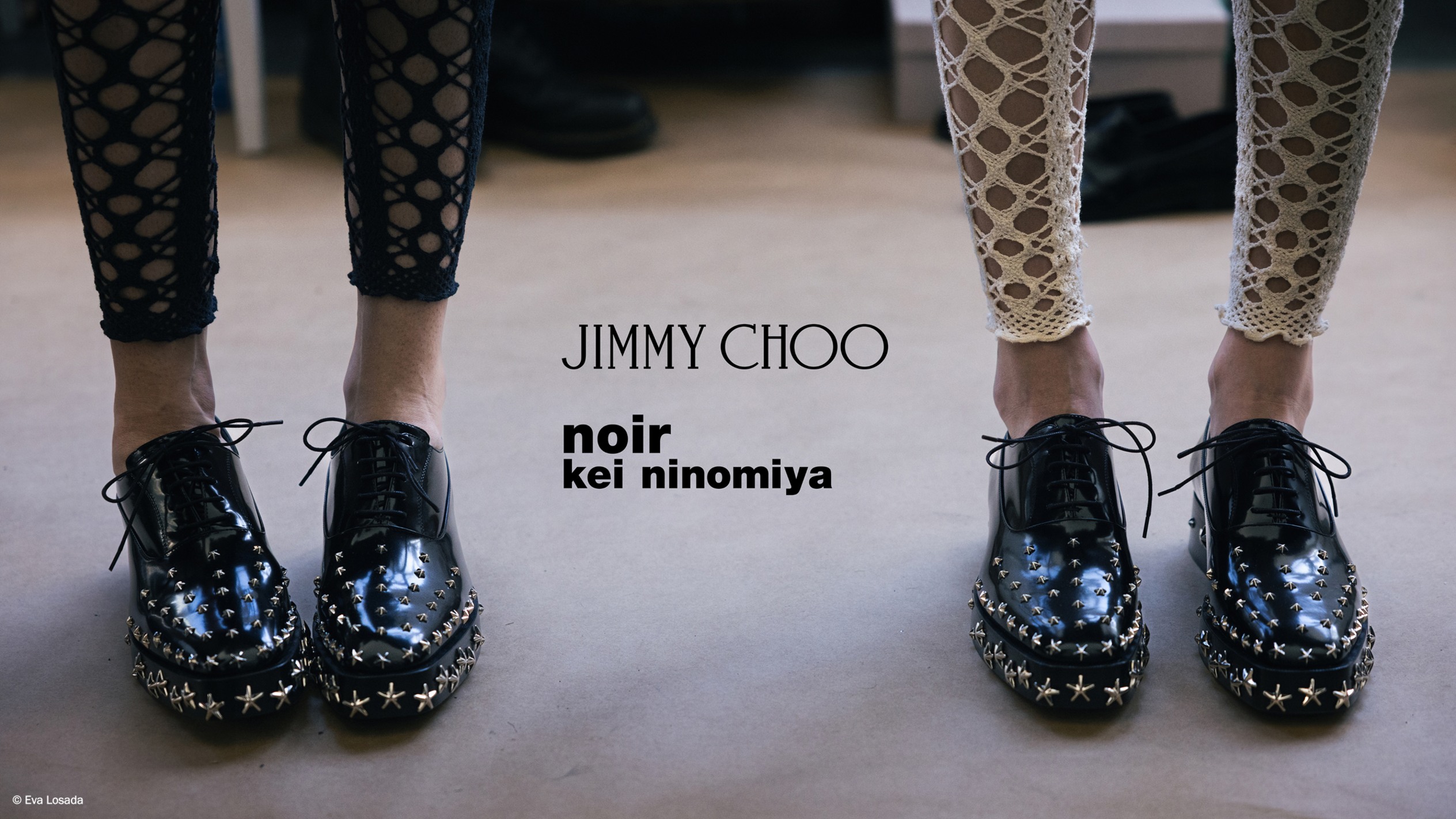 Two pairs of legs wearing black leather star studded lace-up shoes, styled with contrasting cut-out patterned leggings.