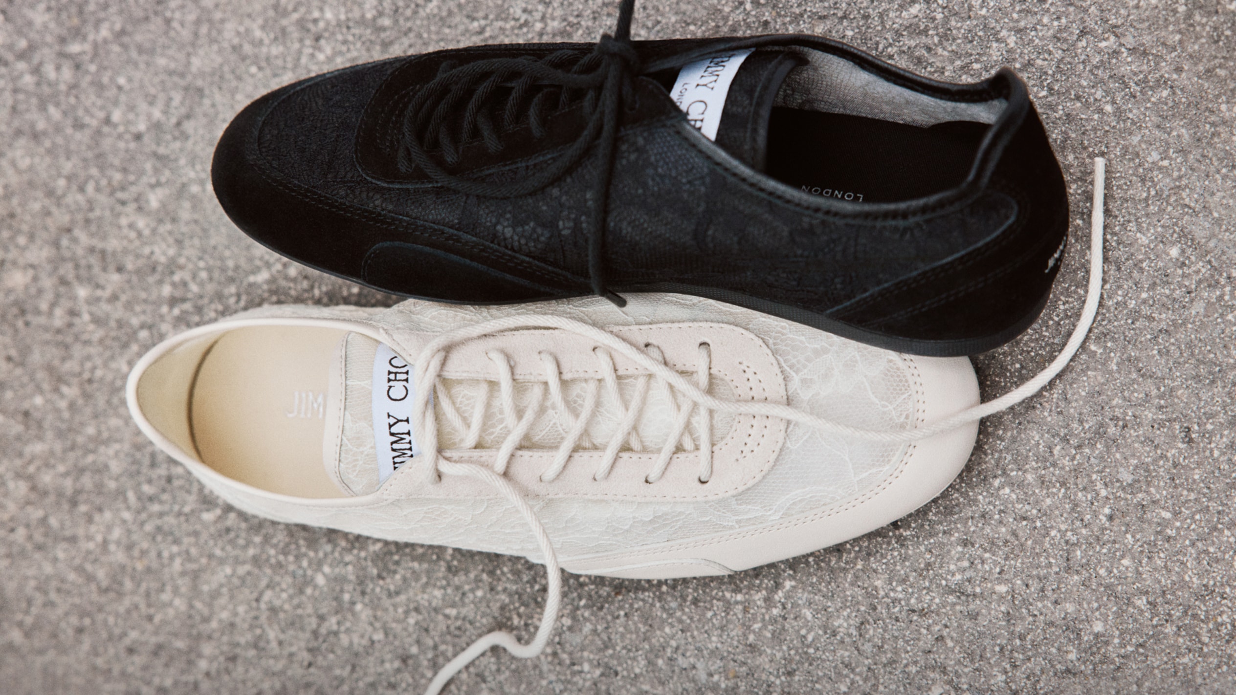 Two pairs of legs wearing black leather star studded lace-up shoes, styled with contrasting cut-out patterned leggings.