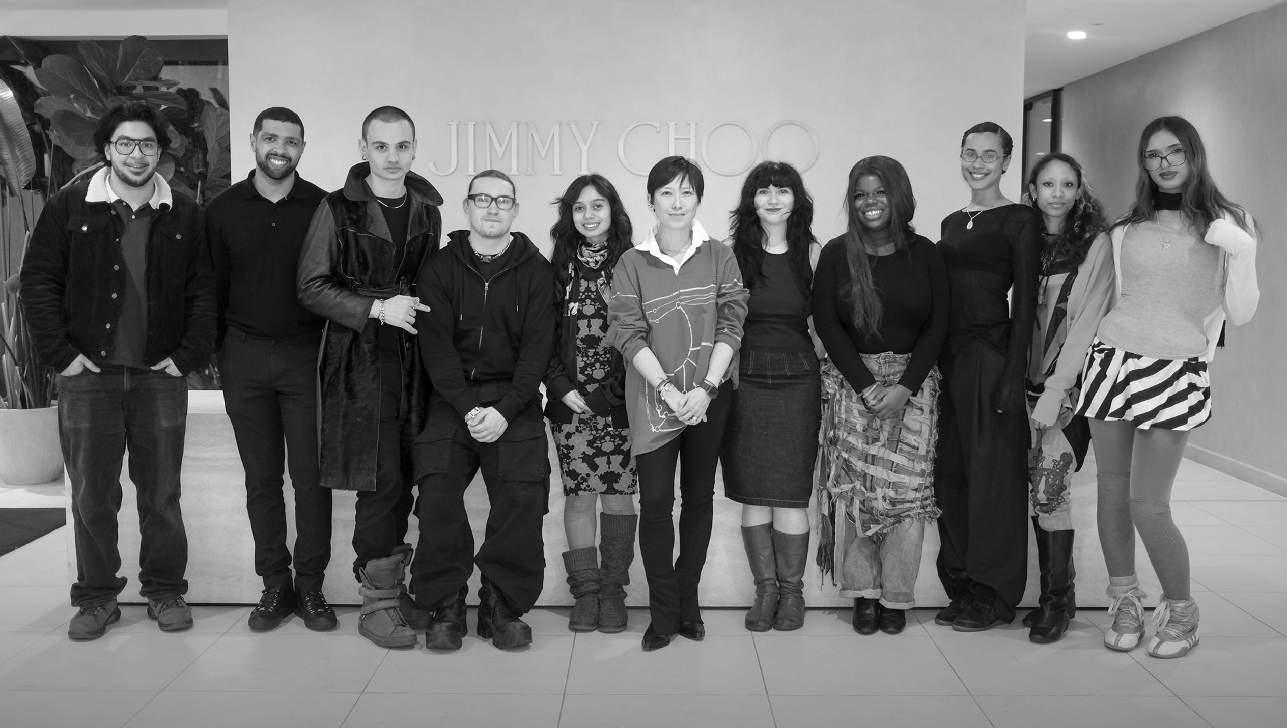 Black and white group photograph of Sandra Choi with Capri Holdings Foundation scholarship recipients at the Jimmy Choo headquarters.