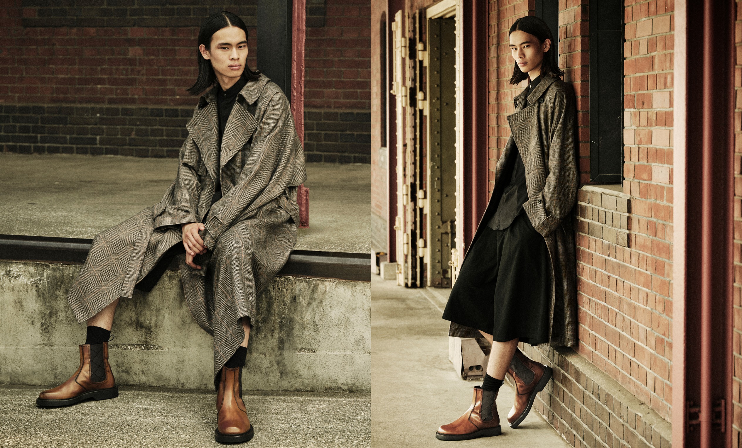 Two male models in layered autumn looks, one in a long pinstripe coat with wide-leg trousers and trainers, the other in a leather jacket styled with tailored shorts and loafers, shot in an architectural walkway.