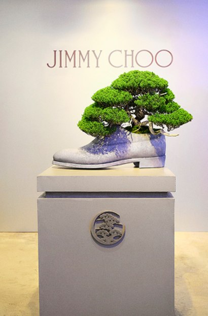 Large boot-shaped planter displayed on a plinth with a bonsai tree growing from the opening.