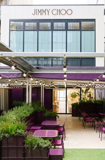 Outdoor seating area at Jimmy Choo Street Cafe Ginza with purple tables and greenery.