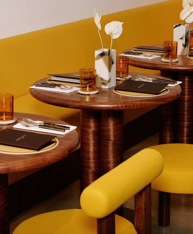  黄色と木目調のインテリアで、メニューやテーブルウェアが並ぶカフェテーブルのクローズアップ。