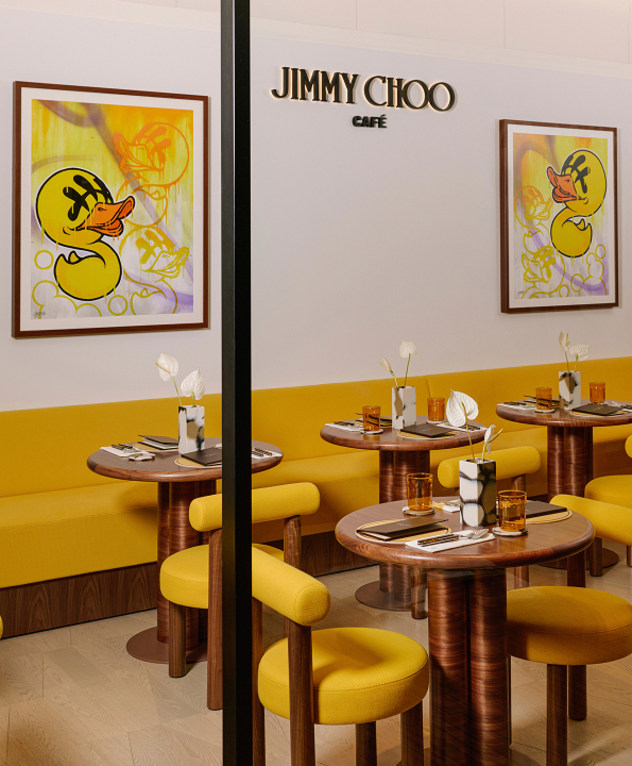  黄色い椅子と壁に飾られたアートワークが並ぶ Jimmy Choo Caf&eacute; のダイニングエリア。