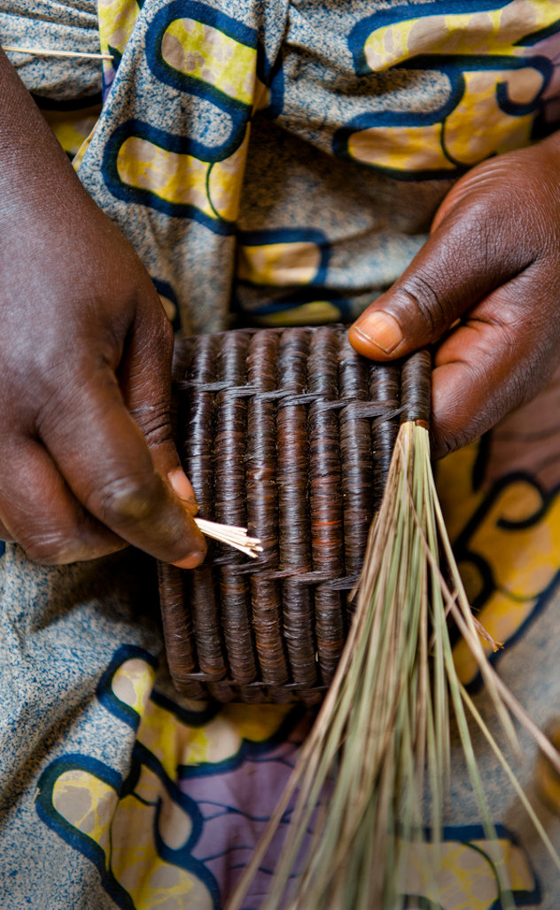 Close-up of hands weaving natural fibres into a basket.