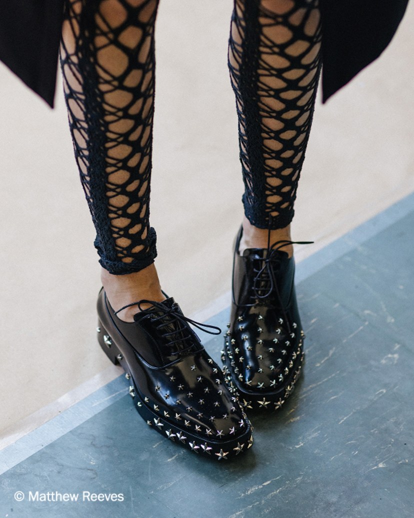 Black leather lace-up shoe with silver star stud embellishment and low block heel, shown in side profile.