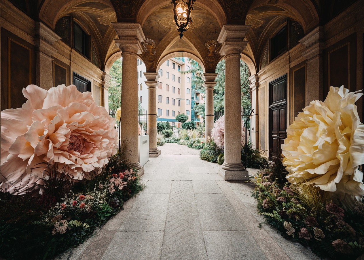 Jimmy Choo installation at Milan Fashion Week Spring 2026, featuring oversized florals and a grand entrance framed by pillars.