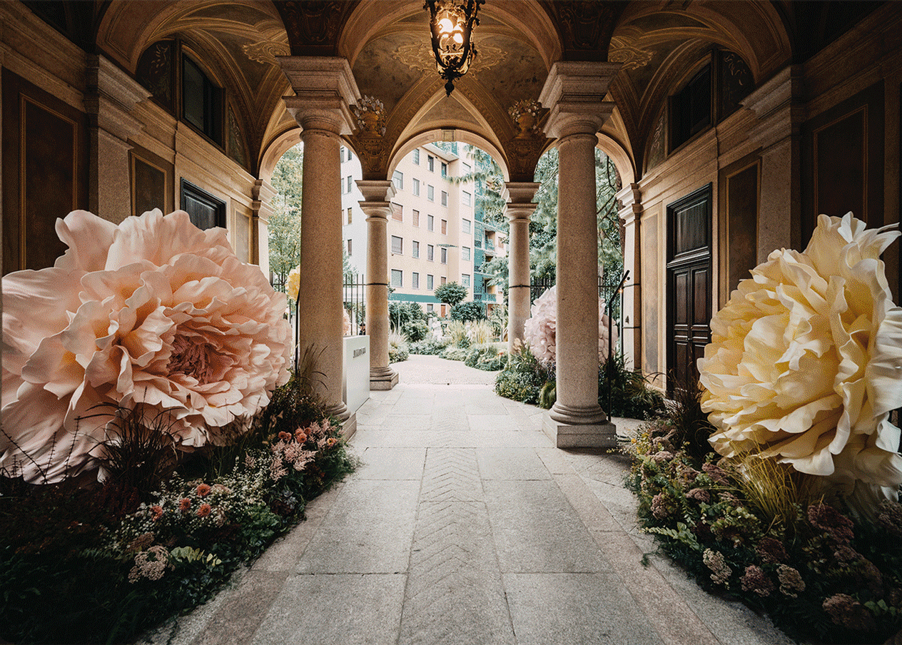 Jimmy Choo installation at Milan Fashion Week Spring 2026, featuring oversized florals and a grand entrance framed by pillars.