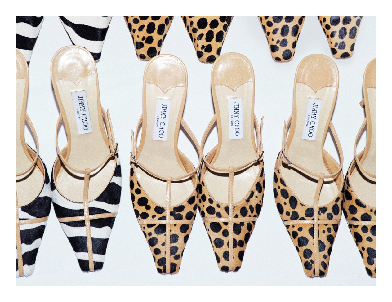 Three pairs of pointed-toe pumps with slender straps, featuring bold animal prints including leopard and zebra, arranged in a flat lay on a white background.