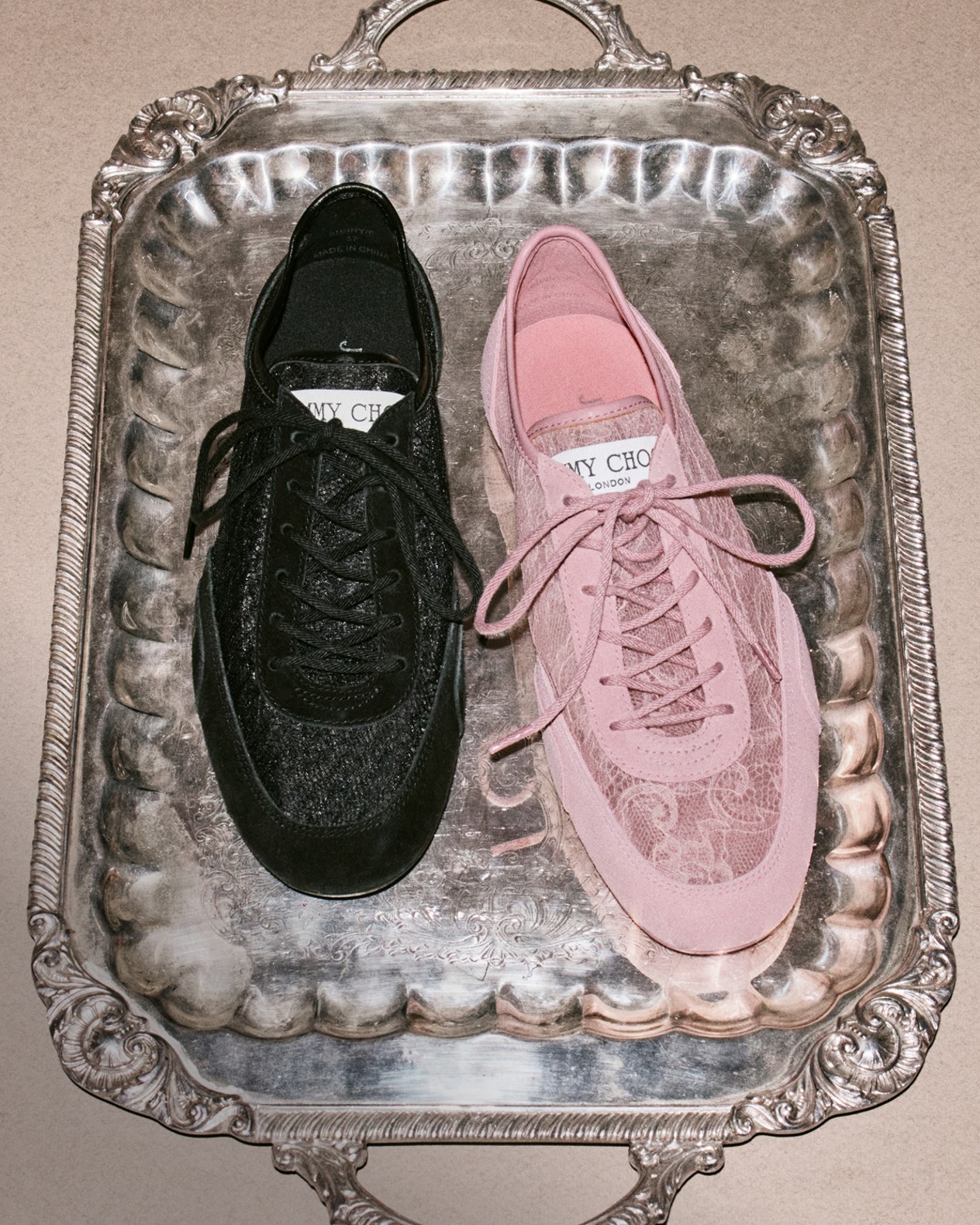 Pair of pointed-toe lace-up pumps, one in black leather and the other in leopard-print pony leather, displayed on a green textured surface.	