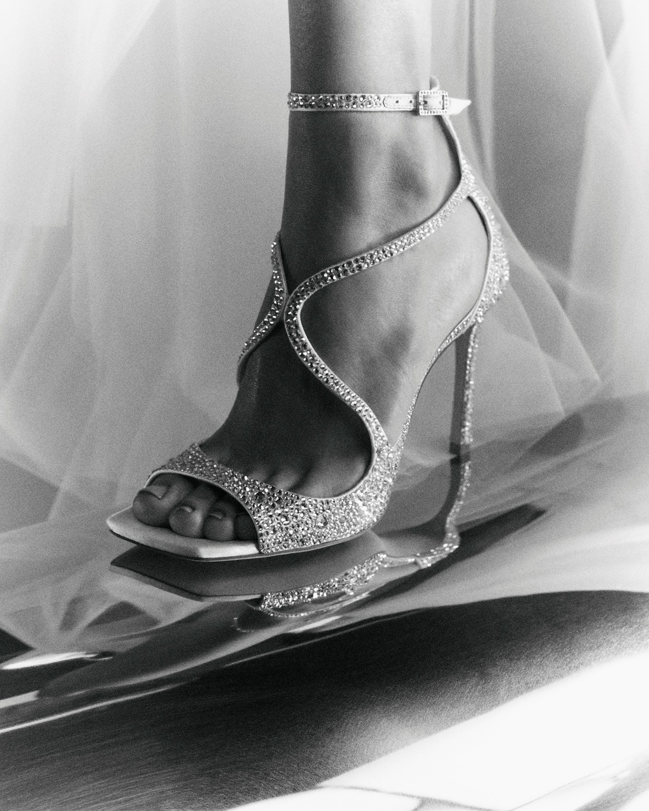  Crystal-embellished strappy heeled sandal with delicate ankle strap, styled beneath sheer tulle.