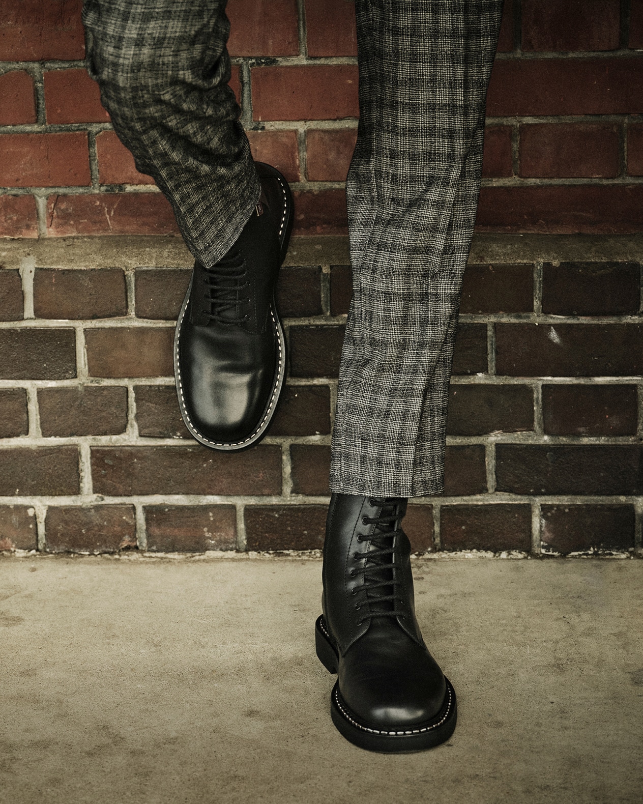 Pair of polished brown leather mens loafers displayed on a deep blue carpet beneath a wooden bench.