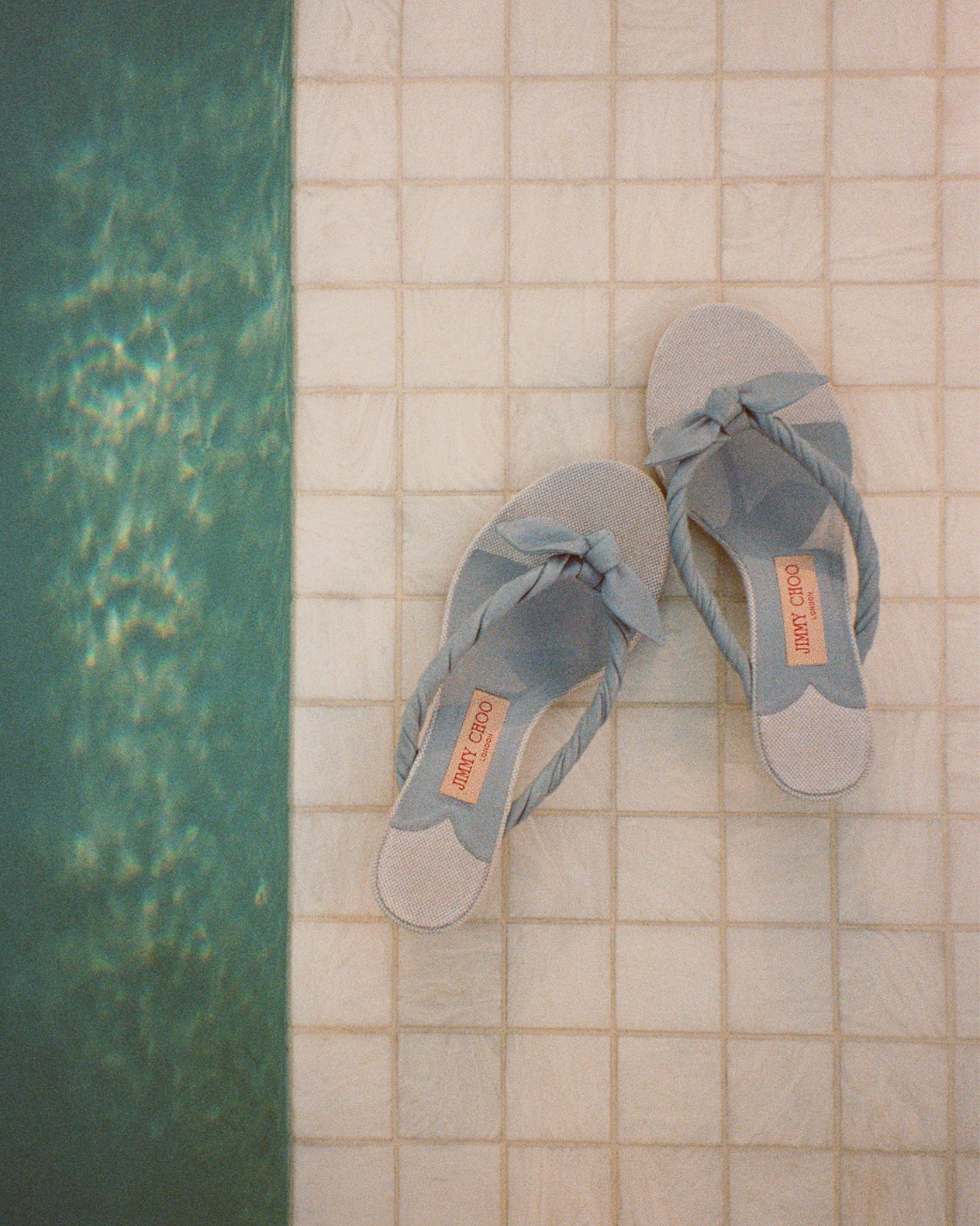 Red gingham and raffia bucket bag with gold bracelet handle resting on a stone ledge.