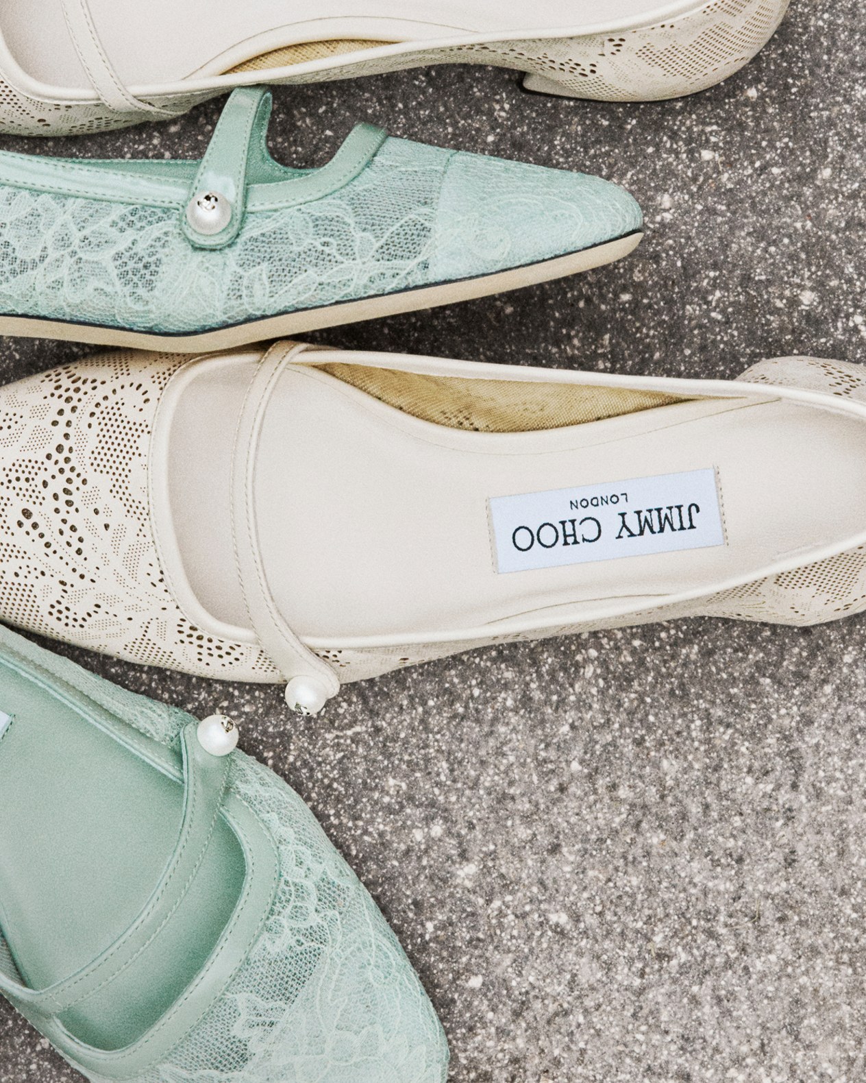 Mint green and cream lace pointed-toe flats, photographed from above on a stone surface.