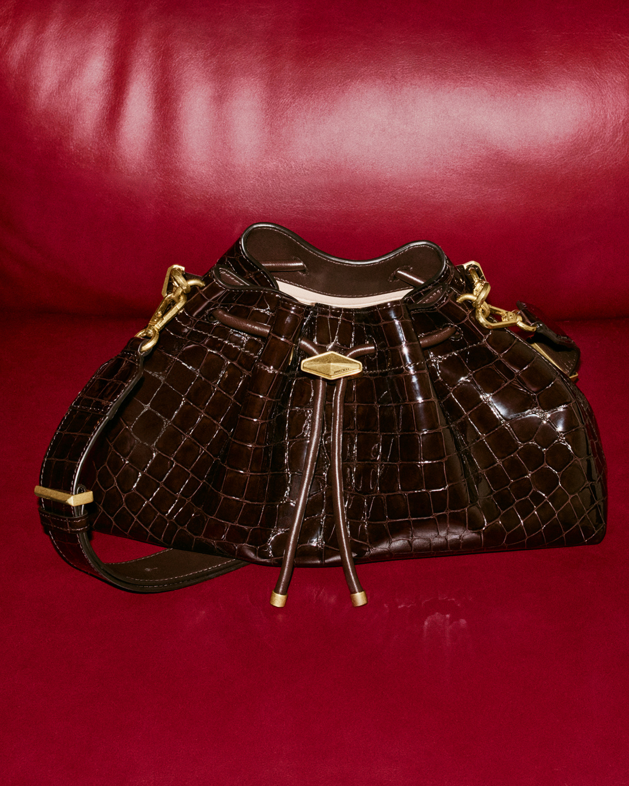 Three Bon Bon bags in red satin, leopard print, and pink satin, styled on a soft blush cushion.