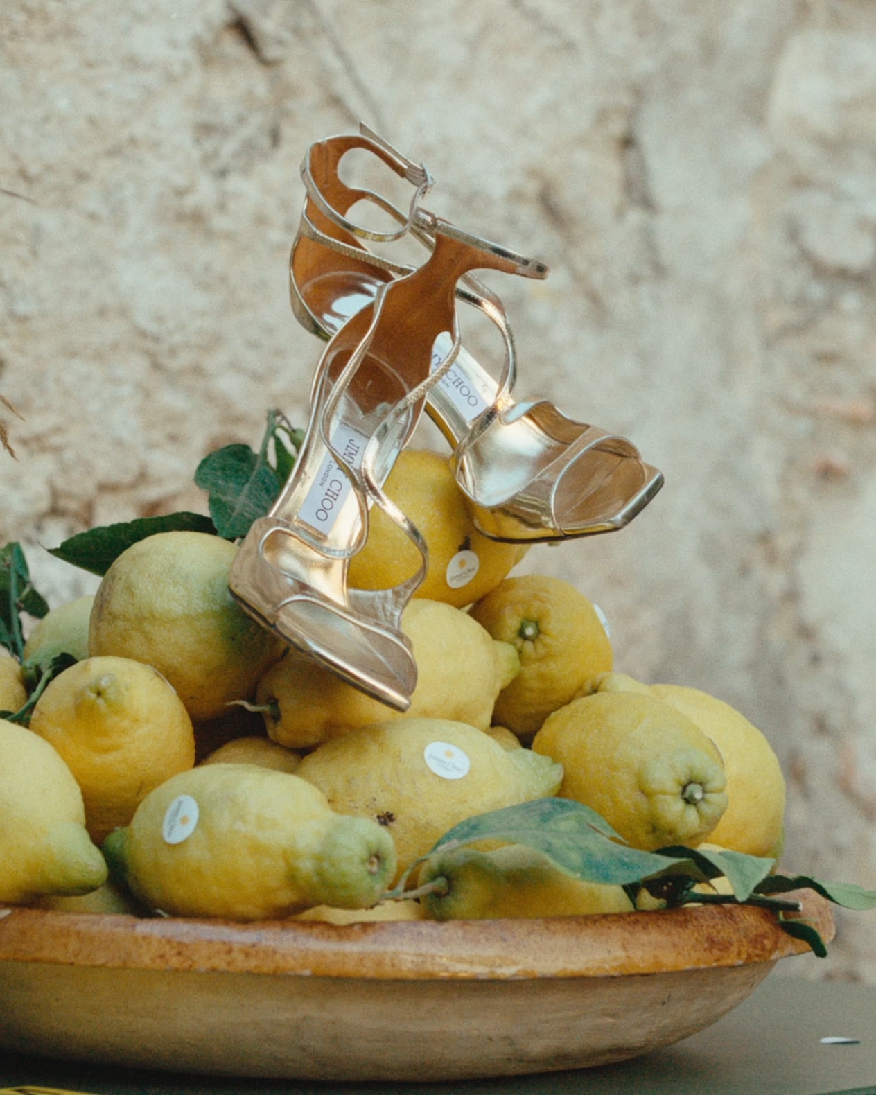 Metallic gold high-heel sandals displayed on a bowl of fresh lemons.