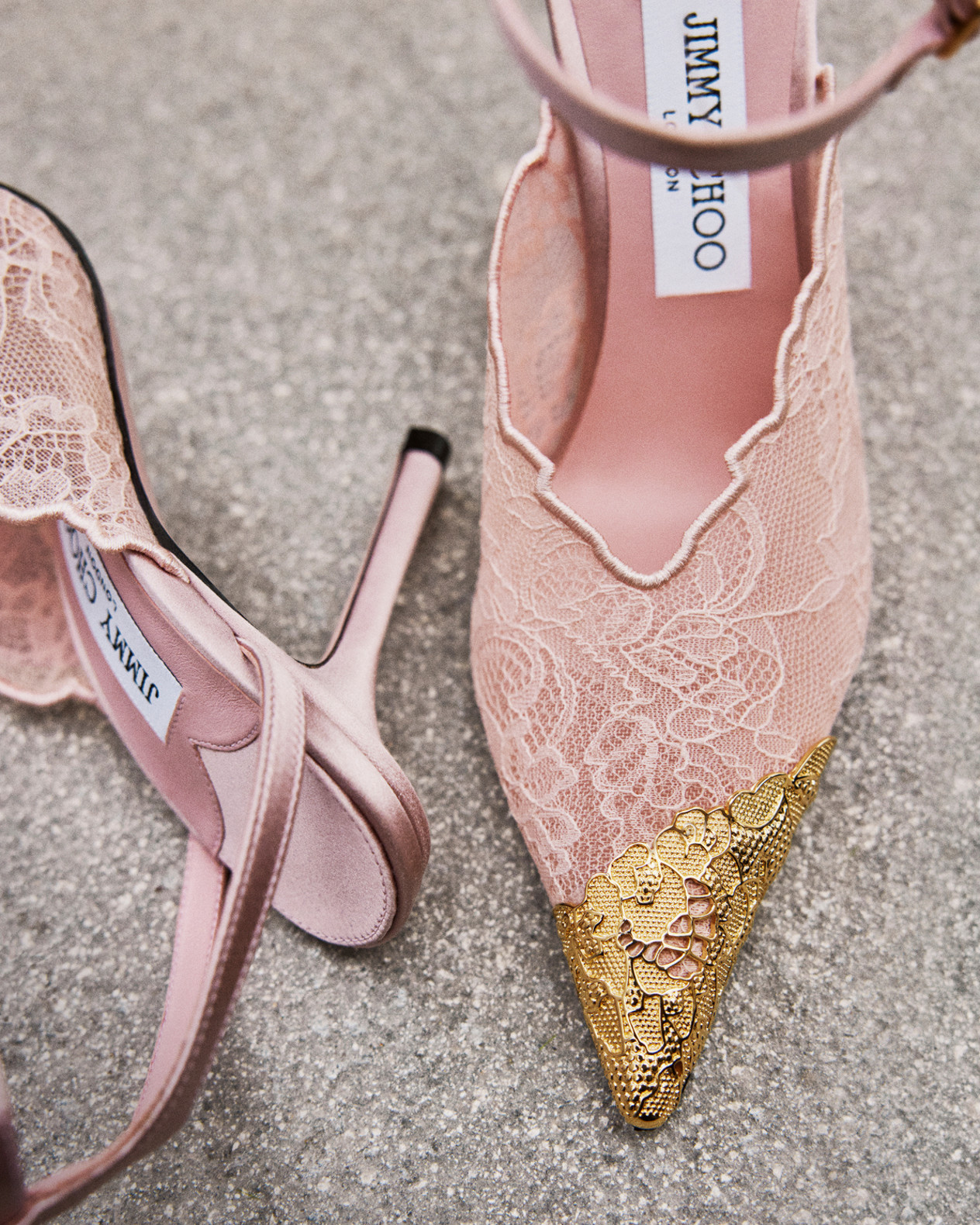 Pointed-toe lace heels with metallic gold cap toe, photographed from above.