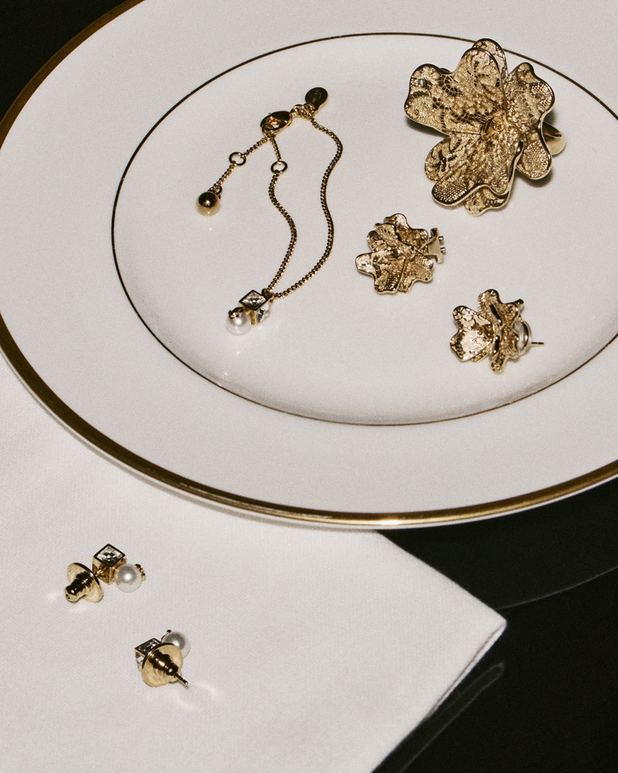 Gold floral jewellery pieces displayed on a fine white plate.
