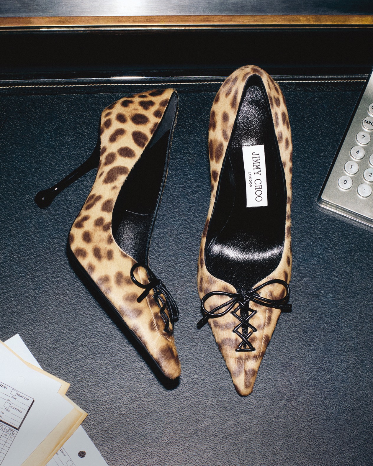 Pair of leopard print lace-up pumps displayed on a reflective surface.