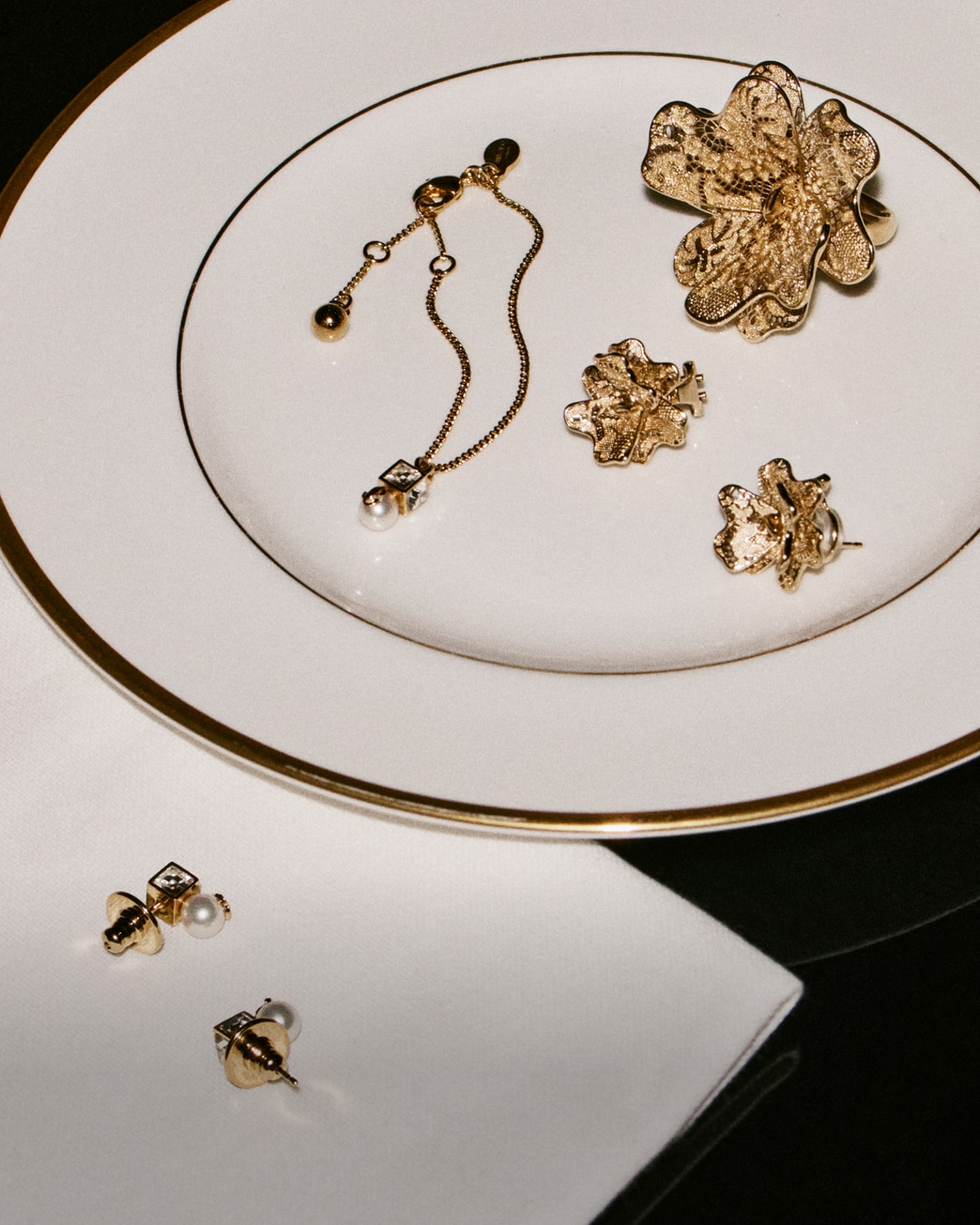 Gold floral jewellery pieces displayed on a fine white plate.