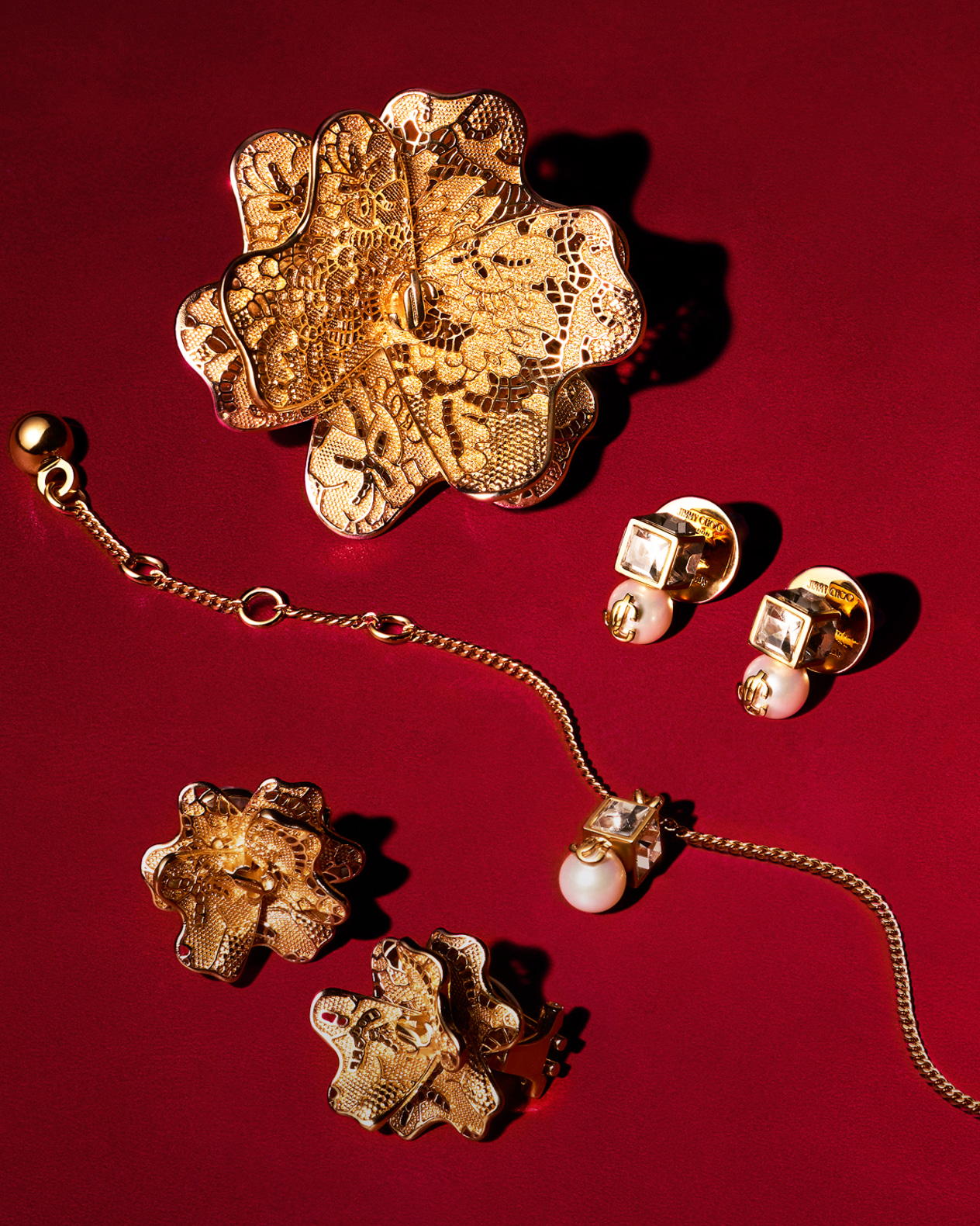 Gold floral jewellery pieces, including earrings and a bracelet with pearl accents, arranged on an elegant white and gold-rimmed plate.	