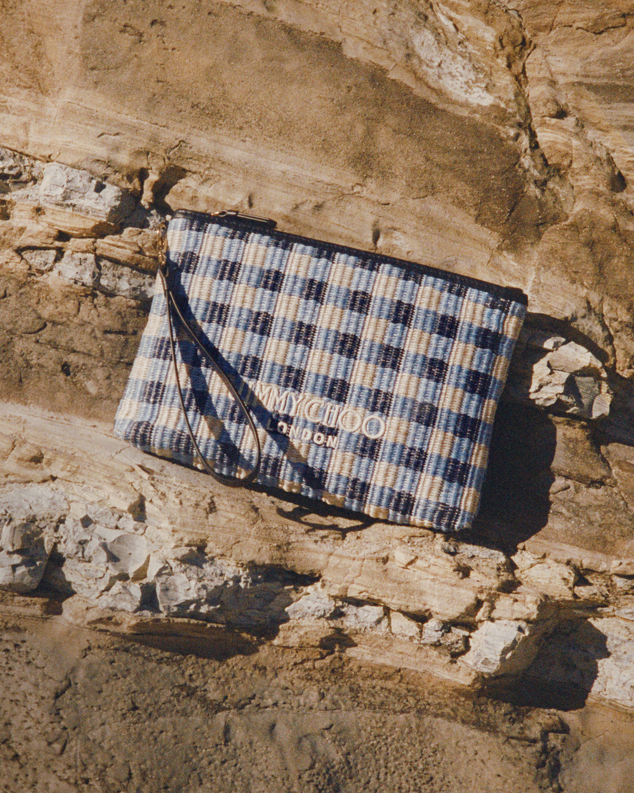 Blue gingham pouch bag placed on rocky coastal terrain.