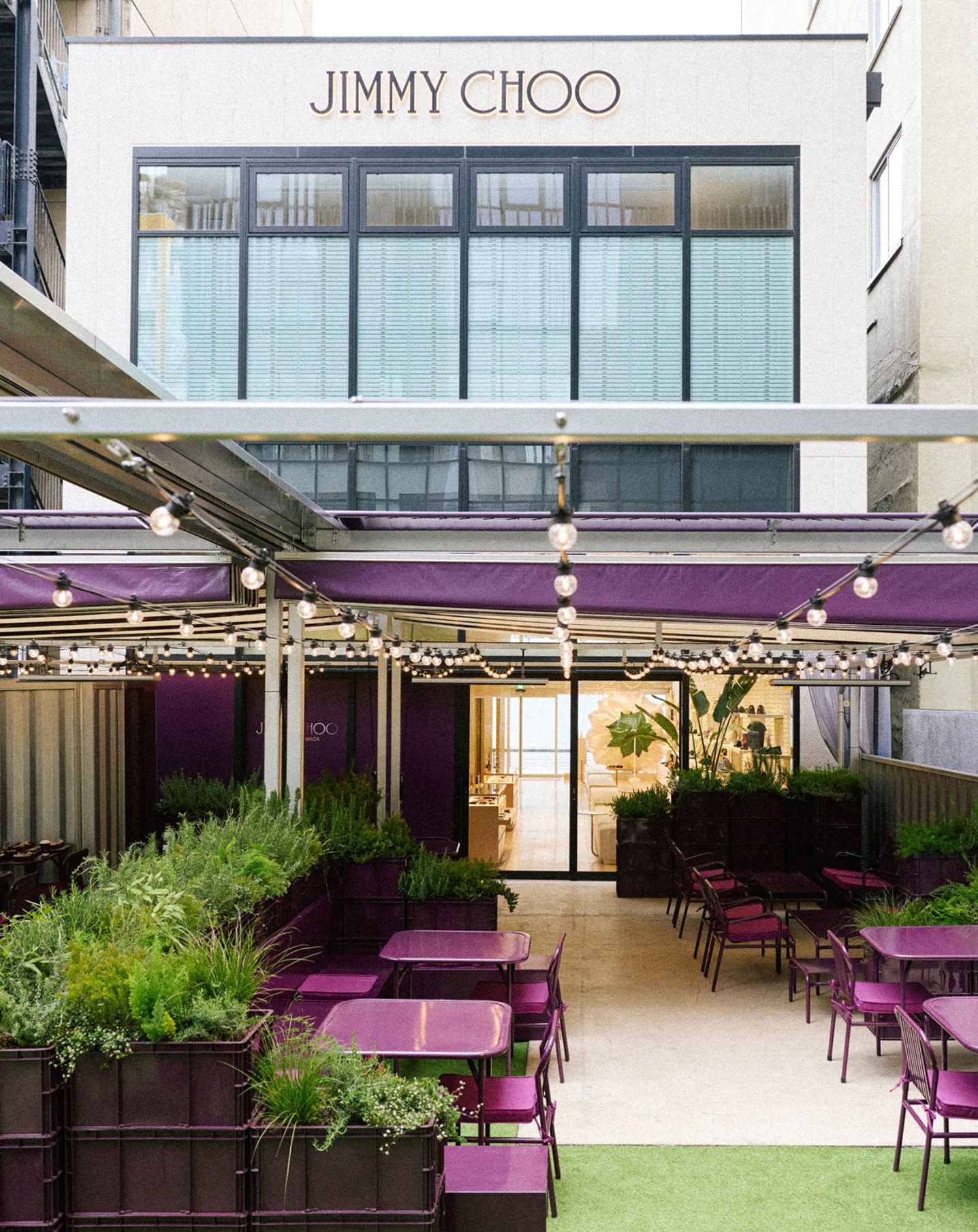 Outdoor seating area at Jimmy Choo Street Cafe Ginza with purple tables and greenery.