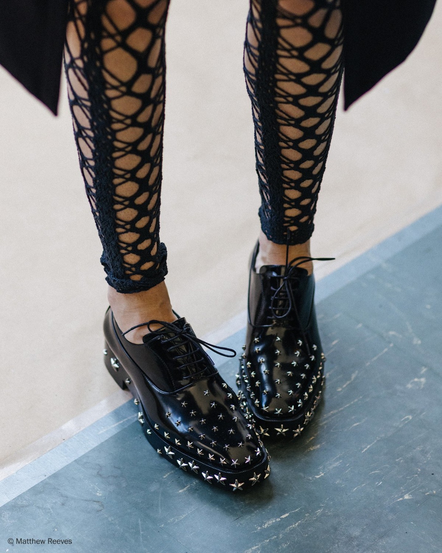 Black leather lace-up shoe with silver star stud embellishment and low block heel, shown in side profile.
