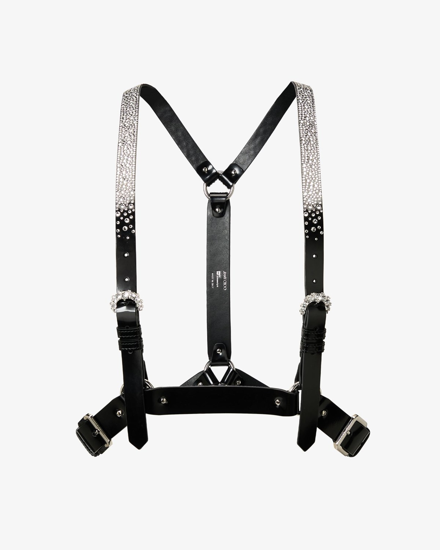 Runway look featuring black leather studded lace-up shoes worn with patterned leggings, a crystal-embellished harness and layered tailoring.