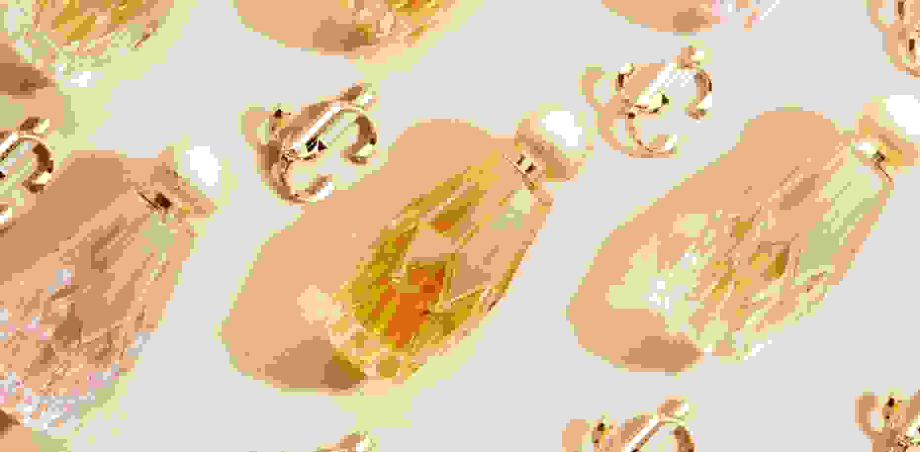 Three fragrances from the Jimmy Choo women’s beauty collection lying next to gold JC emblems