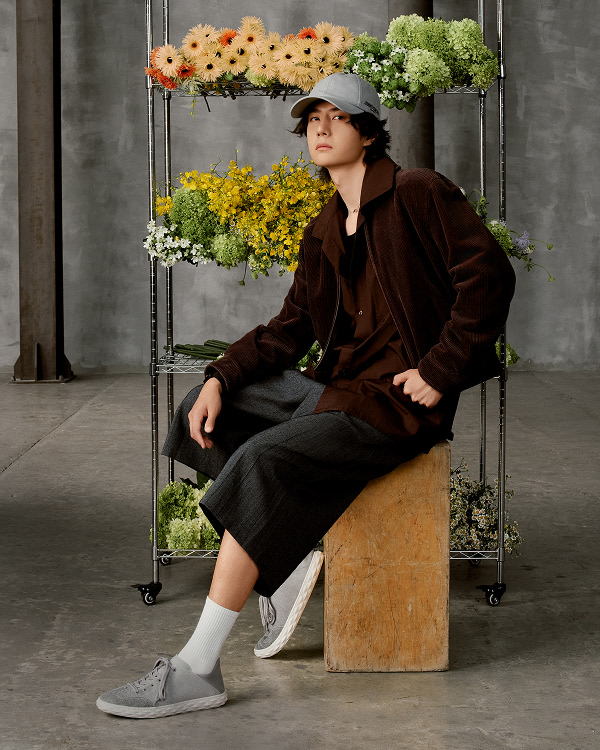 Stack of lace-up trainers in light and dark colourways arranged vertically against a dark background.