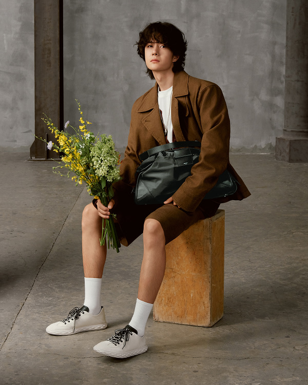 Stack of lace-up trainers in light and dark colourways arranged vertically against a dark background.