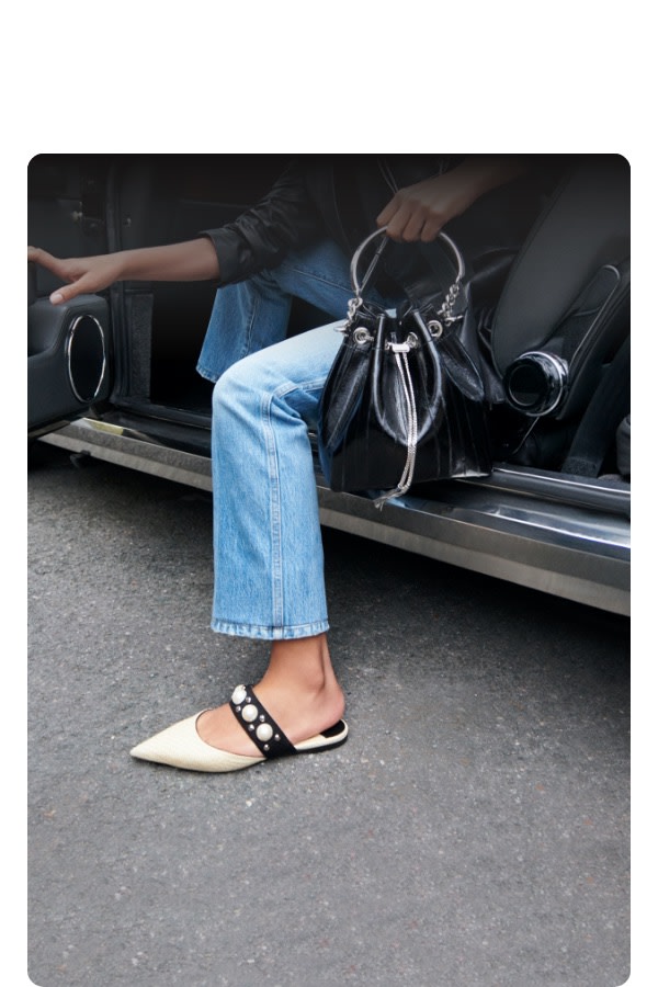 Jimmy Choo women's model with black bag and pearl-embellished flats